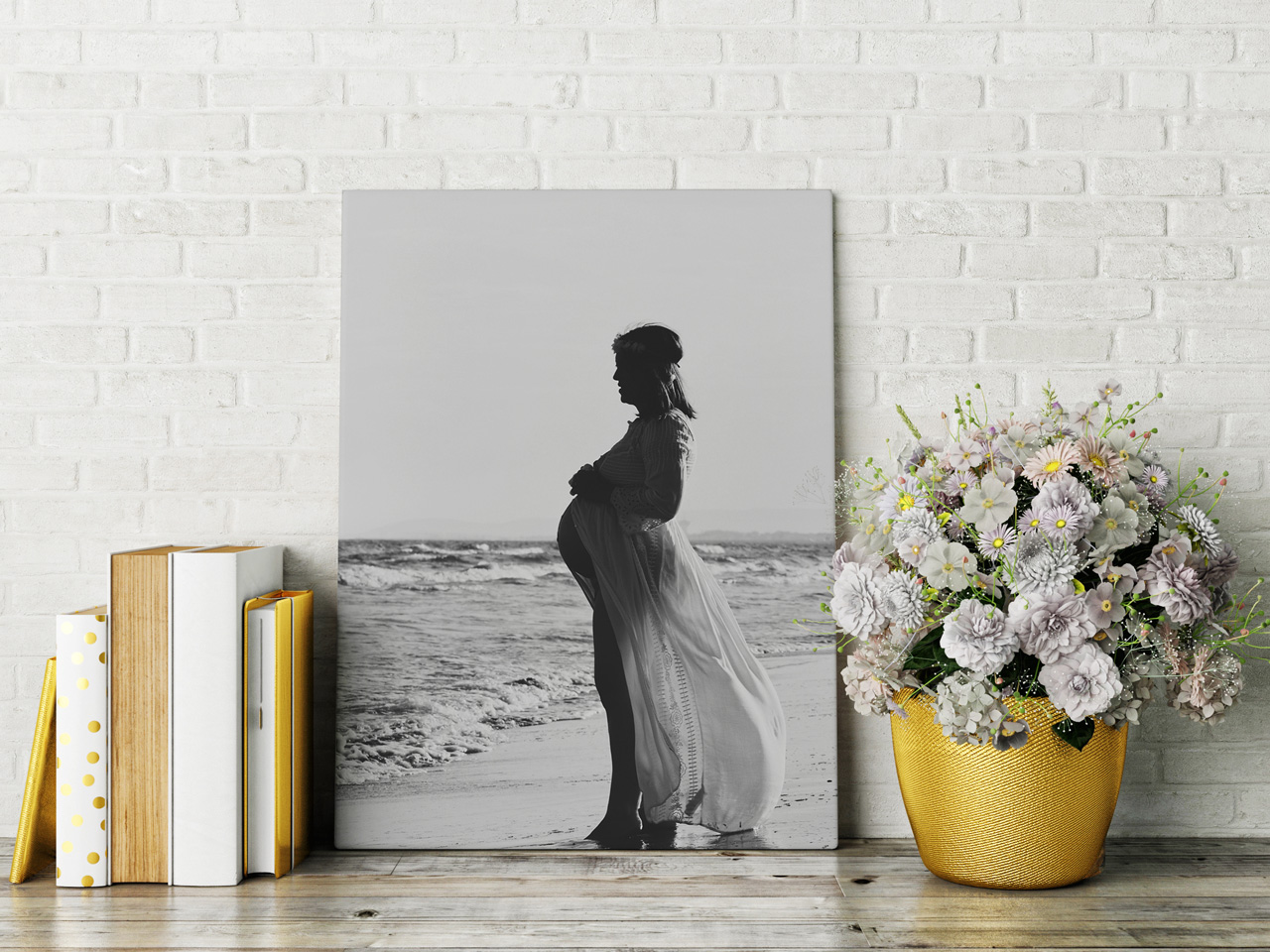 Toile photo personnalisée avec une femme enceinte en noir et blanc sur la plage, posée sur une étagère avec bouquet de fleurs et livres