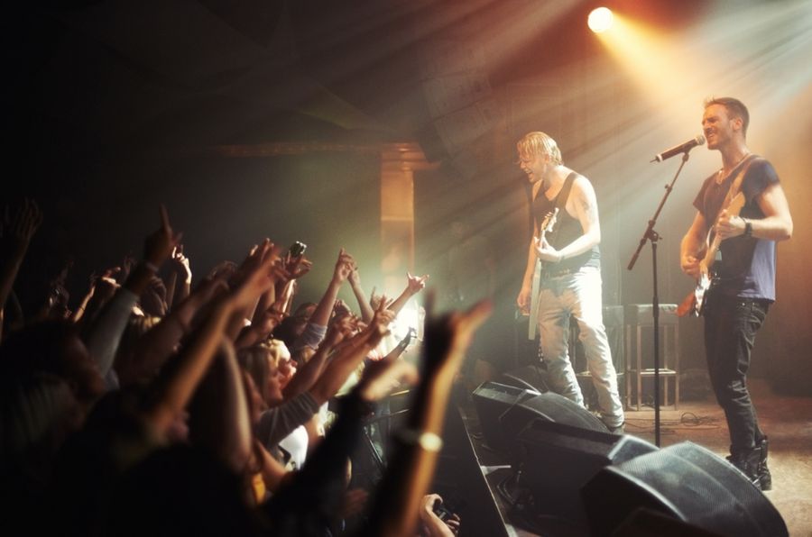 Foule enthousiaste dans la fosse d'un concert de musique, aven un groupe sur la scène