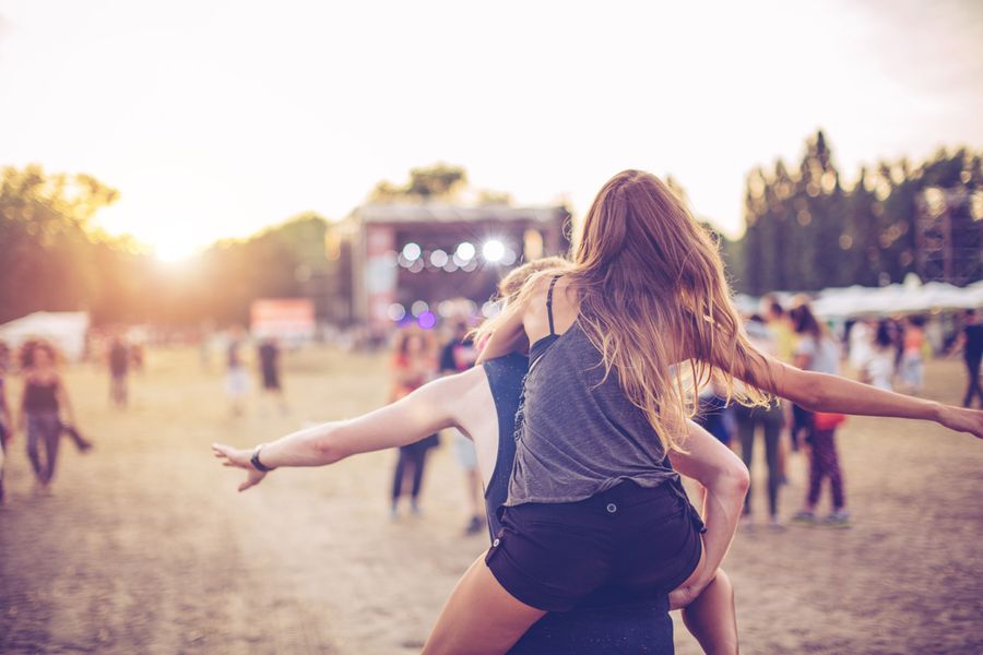 Fille qui porte sa copine dans un concert de musique en extérieur