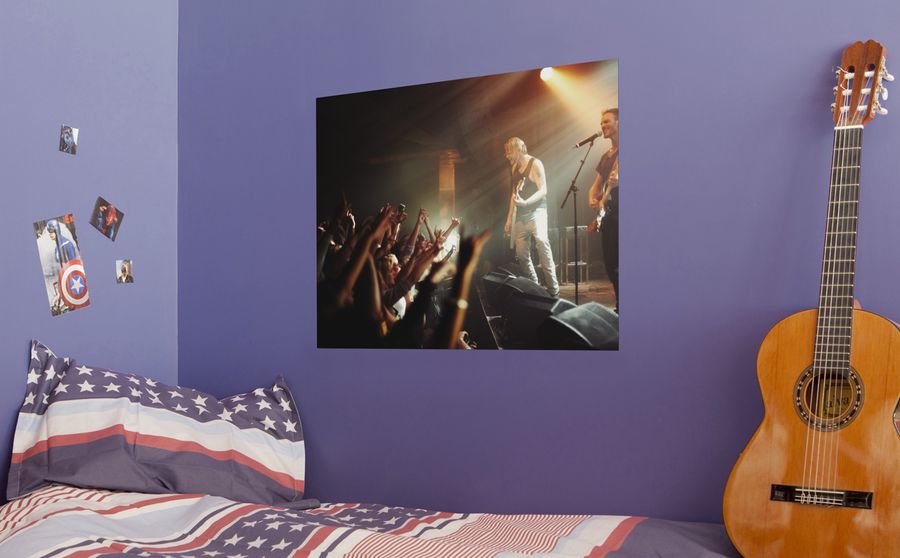 Poster d'une photo de concert dans la chambre d'un adolescent, au dessus du lit