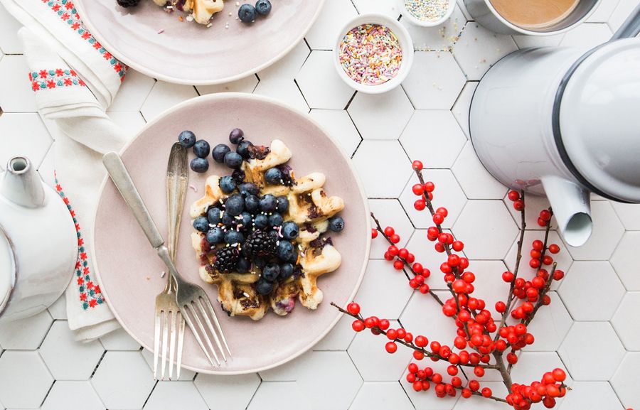 Photographie culinaire d'une gaufre aux myrtilles sur une table en carreaux de faïence