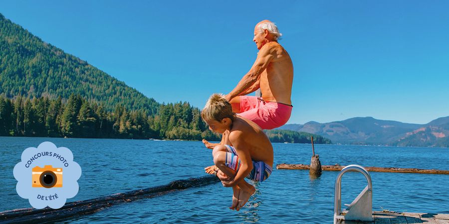 Un homme âgé et un jeune garçon sautent dans la mer, capturant un joyeux moment d’été pour le concours photo d’été Photobox.