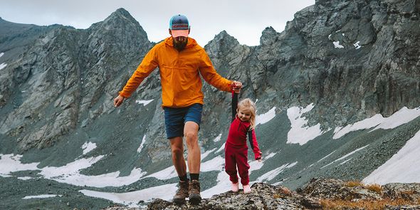 Un père et sa fille marchant dans un paysage montagneux, illustrant un plan d'ensemble et les types de plans en photographie avec Photobox.