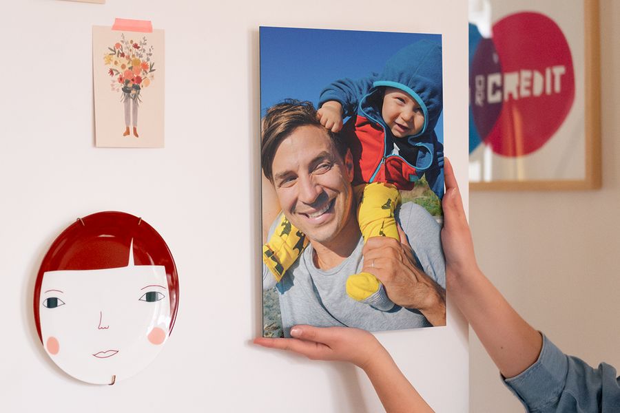 Quelqu'un accrochant un poster personnalisé d'un père et son bébé dans sa déco murale.