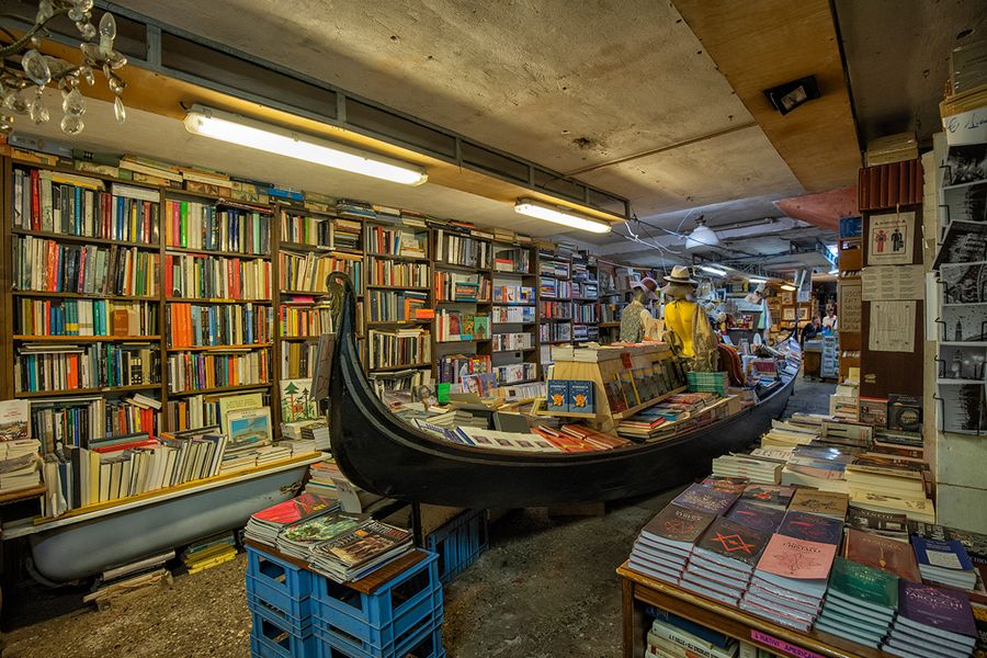 Libreria Acqua Alta à Venise, en Italie, présentant des livres rangés dans une gondole et des baignoires, une librairie insolite pour un voyage littéraire avec Photobox.