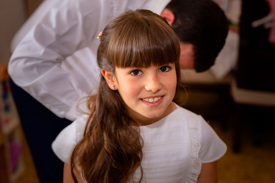 Une jeune fille vêtue d'une robe blanche de première communion, illustrant la préparation de la 1ère communion et le choix des tenues avec Photobox.