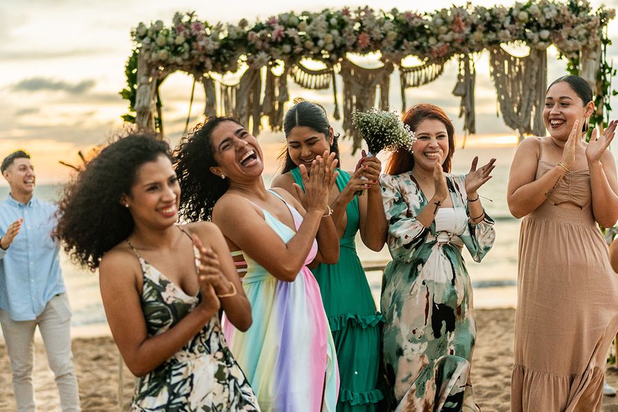 Une photo spontanée d'un mariage à la plage avec des invités qui rient, illustrant l'esthétique paparazzi et les tendances actuelles en photographie de mariage avec Photobox.