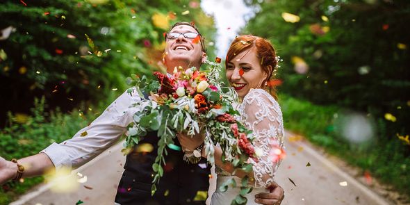 Un couple heureux célébrant leur mariage à l'extérieur sous une pluie de confettis, illustrant les tendances mariage 2026 et la fin des traditions guindées avec Photobox.