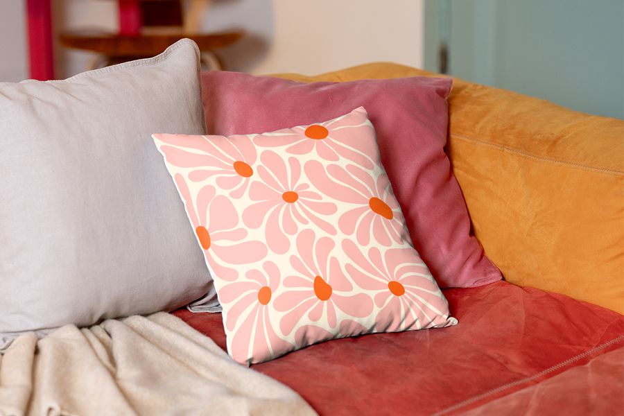 Un coussin rose à fleurs personnalisé sur un canapé, illustrant une idée de décoration de salon pour locataires avec Photobox.