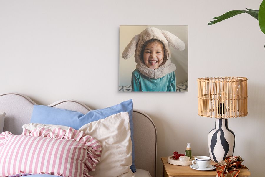 Un tirage rétro d'une jeune fille dans une chambre colorée, montrant comment accrocher un tableau sans trou et personnaliser son espace avec Photobox.