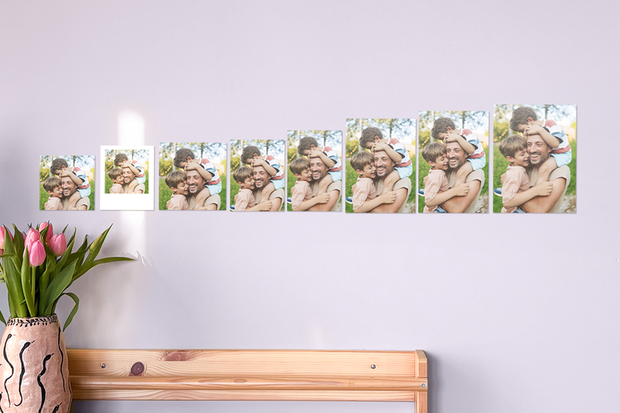 Des tirages photo Photobox montrant la même photo d’un père et de ses fils qui s’enlacent, présentés en différents formats sur un mur, avec des tirages photo standard, des tirages photo carrés et des tirages photo grand format pour aider à choisir le bon format avant de commander des tirages photo en ligne.