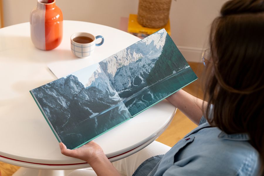 Un livre photo Photobox de type beau livre ouvert, montrant une double page avec un paysage de lac entouré de montagnes, pour inspirer un beau livre photo et un livre photo décoratif personnalisé.