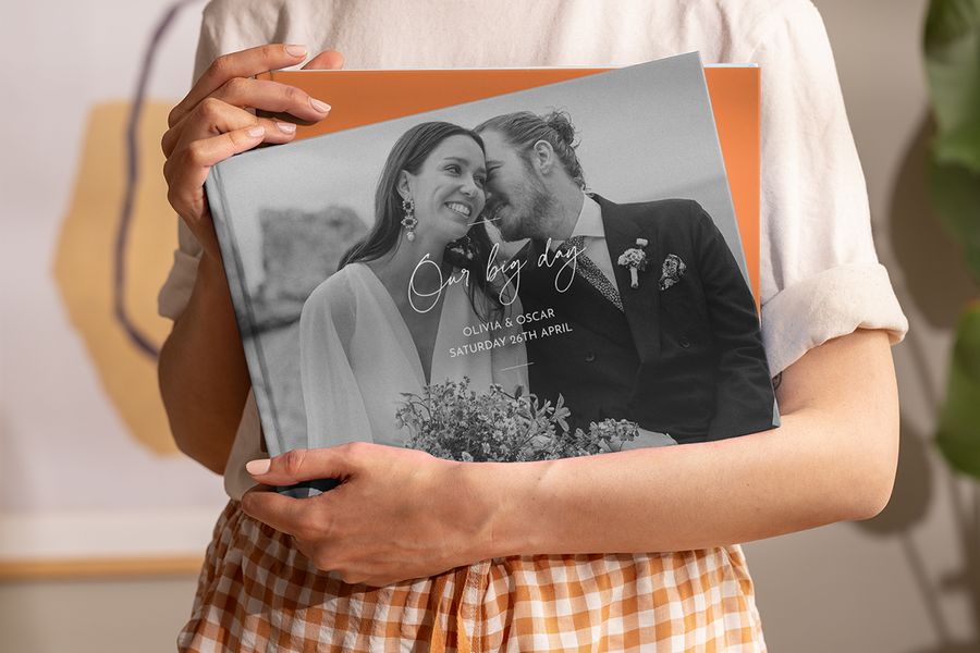 Une femme tient dans ses mains un livre photo Photobox de mariage de type beau livre personnalisé, pour inspirer un beau livre photo de mariage et un livre photo décoratif personnalisé.