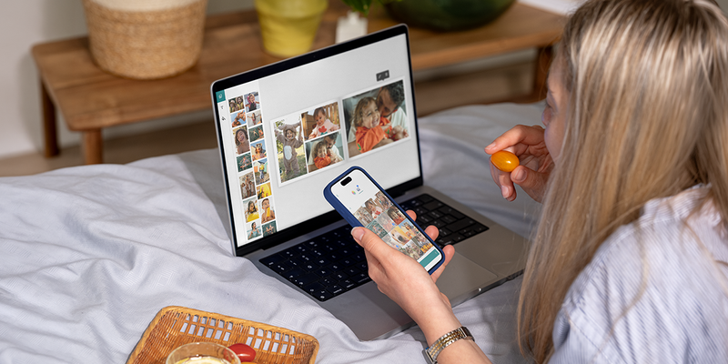 Une femme utilise l’éditeur de bureau Photobox sur son ordinateur portable tout en mangeant une tomate cerise pour créer un livre photo personnalisé, pour inspirer une création livre photo facile et un livre photo facile.