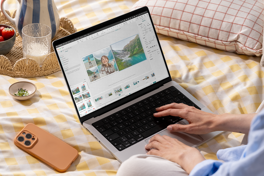 Une personne utilise l’éditeur de livre photo Photobox sur un ordinateur portable dans son lit, pour inspirer un livre photo facile et une création livre photo facile.