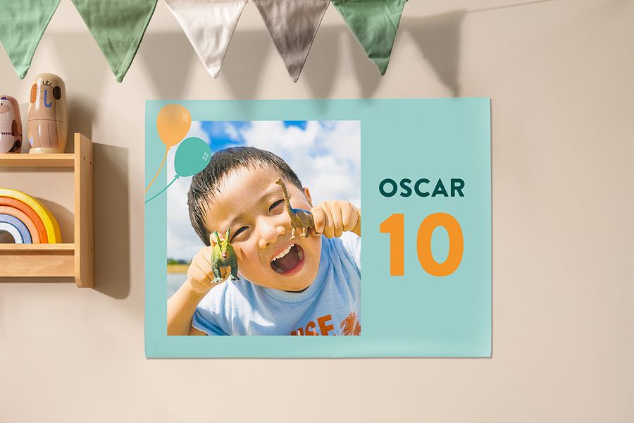 Une affiche personnalisée Photobox utilisée comme décoration lors d’une fête d’anniversaire enfant, montrant un petit garçon tenant des dinosaures pour fêter ses 10 ans, pour inspirer une fête enfant et une décoration personnalisée.