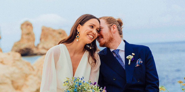 Un couple de mariés souriant sur la plage le jour de son mariage, pour inspirer Photobox et des jeux mariage pour animer un mariage.