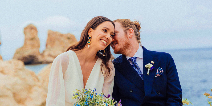 Un couple de mariés souriant sur la plage le jour de son mariage, pour inspirer Photobox et des jeux mariage pour animer un mariage.