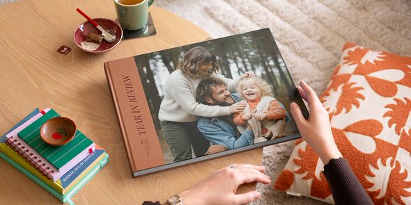 Un livre photo Photobox de type beau livre retraçant l’année, avec une belle photo de famille en couverture, posé sur une table basse comme source d’inspiration pour un livre photo décoratif personnalisé.
