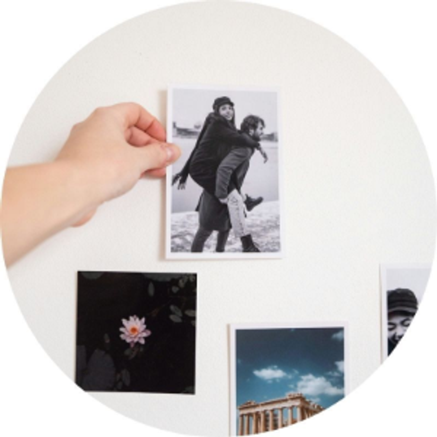 Une main tient un tirage photo d’un couple à côté d’autres tirages photo, illustrant l’histoire de demande en mariage d’Andrea et une idée de demande pleine de souvenirs avec Photobox.