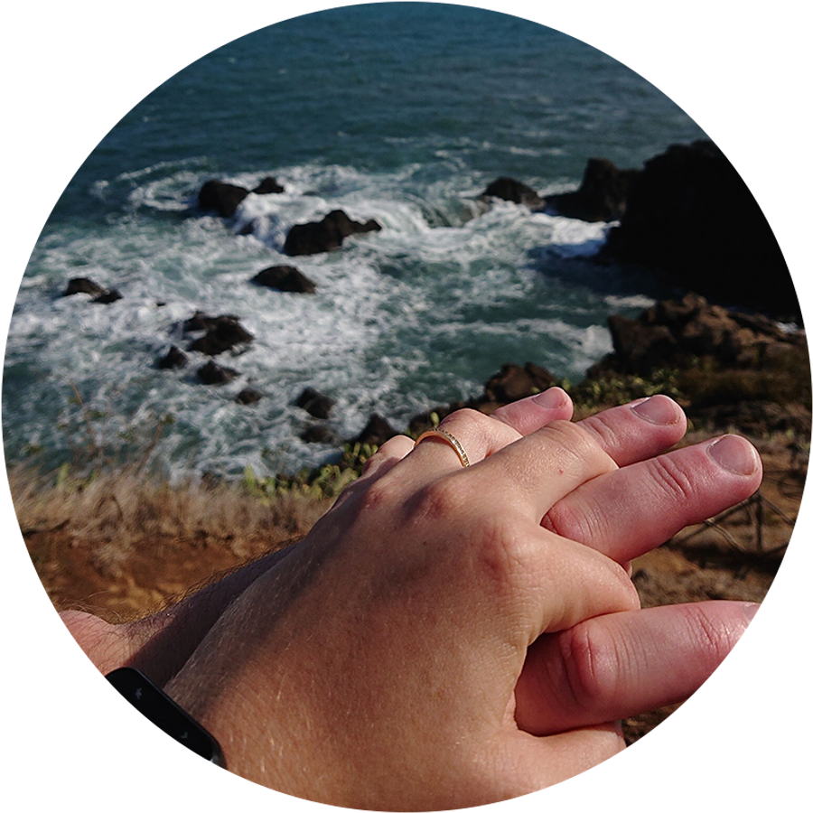 Deux mains enlacées au bord de la mer à Madère, dont l’une porte une bague de fiançailles, illustrent l’histoire romantique de la demande en mariage de Kamilla pendant ses vacances.