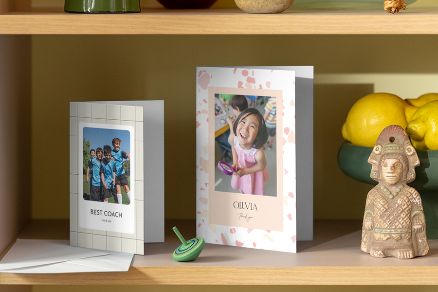 Deux cartes de remerciement personnalisées Photobox pour enseignants sont exposées sur une étagère dans une maison.