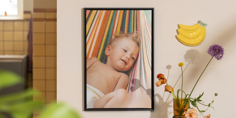 Une décoration murale personnalisée Photobox montrant la photo d’un bébé à côté de fleurs et de fruits, pour inspirer une déco été lumineuse et pleine de fraîcheur.