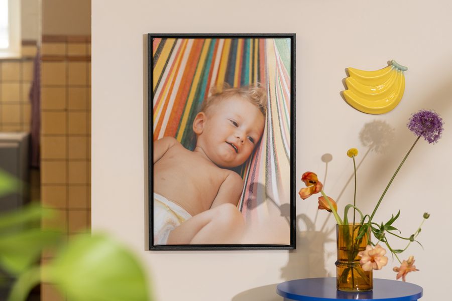 Une décoration murale personnalisée Photobox montrant la photo d’un bébé à côté de fleurs et de fruits, pour inspirer une déco été lumineuse et pleine de fraîcheur.