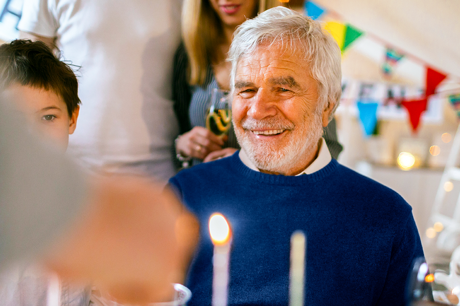 Un grand-père souriant lors de la célébration de son anniversaire, illustrant une idée cadeau anniversaire homme ou un cadeau personnalisé anniversaire de Photobox.