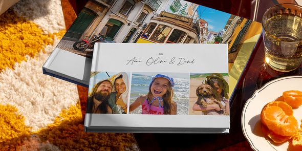 Deux livres photo voyage Photobox différents sont présentés ensemble, dont un album photo voyage au format paysage avec des photos de voyage en famille sur la couverture et un autre avec une photo de tramway, montrant différents styles de livre photo vacances personnalisé.