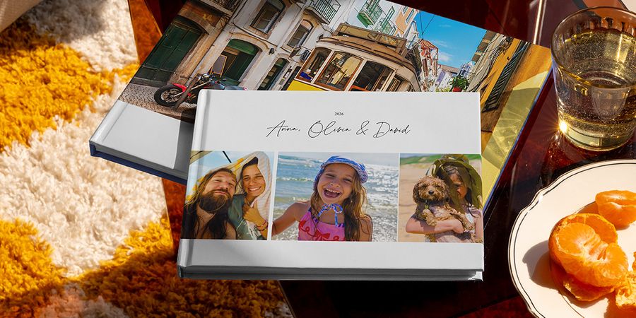 Deux livres photo voyage Photobox différents sont présentés ensemble, dont un album photo voyage au format paysage avec des photos de voyage en famille sur la couverture et un autre avec une photo de tramway, montrant différents styles de livre photo vacances personnalisé.