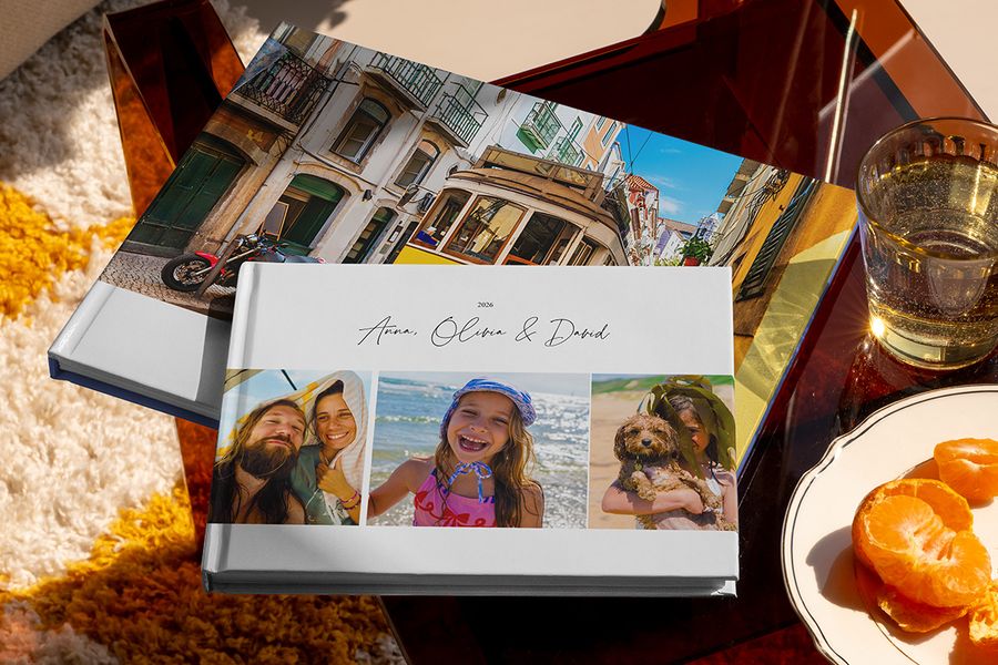 Deux livres photo voyage Photobox différents sont présentés ensemble, dont un album photo voyage au format paysage avec des photos de voyage en famille sur la couverture et un autre avec une photo de tramway, montrant différents styles de livre photo vacances personnalisé.