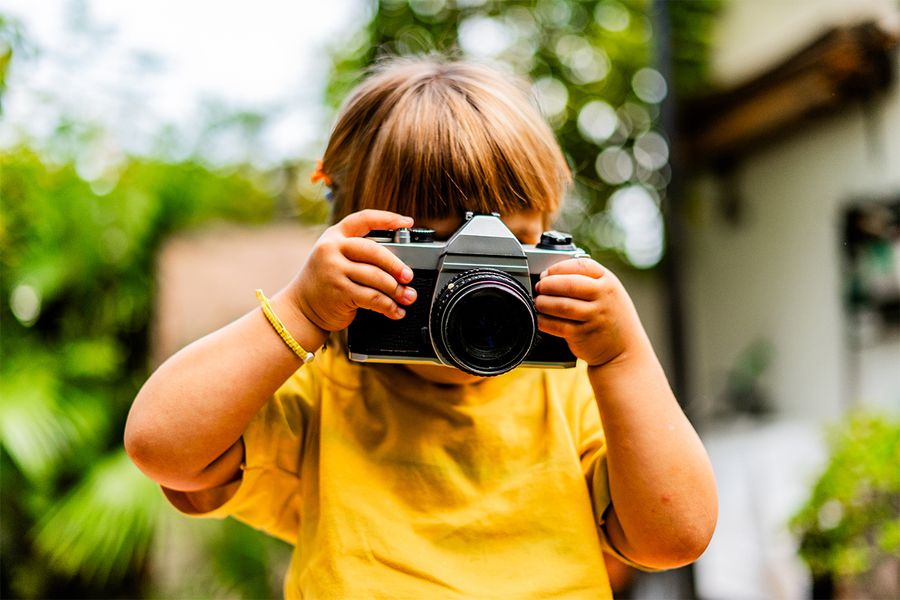 Une jeune fille prend des photos avec un appareil photo, illustrant les idées de vacances à la maison créatives de Photobox.