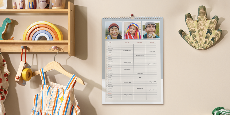 Un organiseur familial est exposé dans une cuisine familiale, illustrant le voyage en famille, l’organisation des vacances et des idées de jeux en famille avec Photobox.