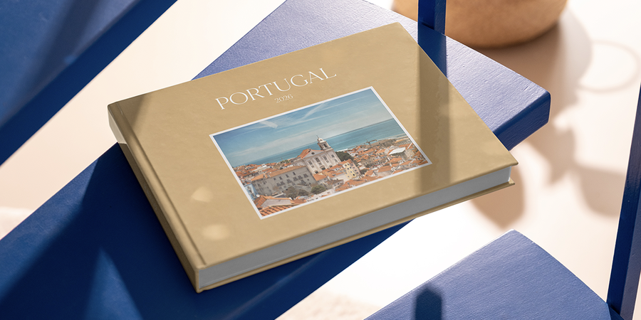 Un livre photo de famille personnalisé Photobox intitulé Portugal 2026 est posé sur une table, capturant des souvenirs de voyage en famille et une belle façon de garder ces moments.