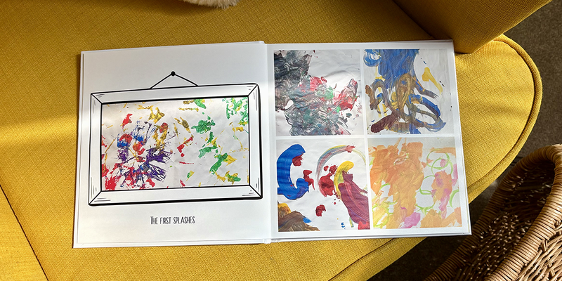 Un livre photo pour enfant ouvert repose sur un fauteuil jaune, avec sur la page de gauche les premières éclaboussures de peinture d'un jeune enfant et sur la page de droite quatre peintures différentes, illustrant les idées de Photobox pour un album photo enfant.
