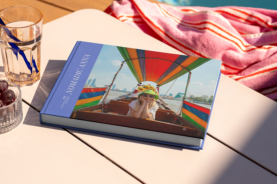 Un livre photo avec un canal et des maisons colorées en Italie sur la couverture s'intitule 'Ciao from the Land of Pasta', illustrant les idées de titre album photo voyage en ville de Photobox.