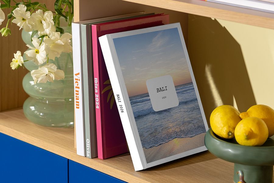 Le nouveau livre photo Modern Travelogue de Photobox est posé sur une étagère, illustrant des mises en page épurées et une typographie élégante inspirées des magazines de voyage et des livres de table basse.