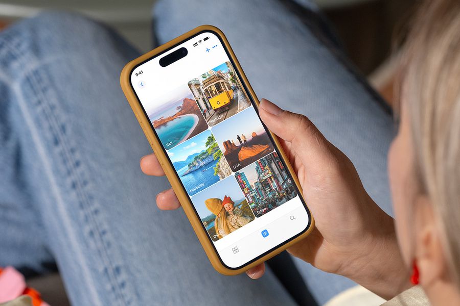 Une personne consulte des dossiers photo sur son téléphone portant des noms de destinations de vacances comme « Bali » et « Tokyo », illustrant les conseils de Photobox pour organiser ses photos avant de les imprimer.