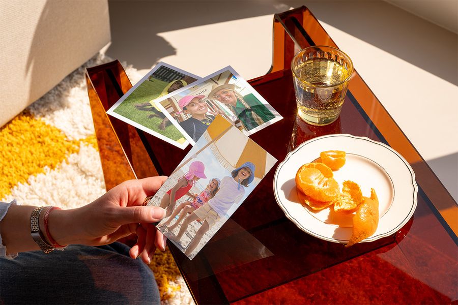 Une personne regarde une sélection de jolis tirages photo, illustrant comment Photobox peut aider à transformer des photos organisées en souvenirs à chérir.