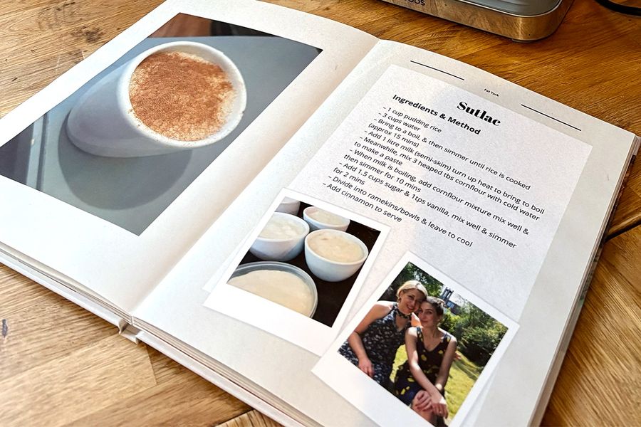Le livre de recettes ouvert de Sarah est posé sur le plan de travail de la cuisine, révélant son format de livre photo layflat, avec des images de riz au lait turc sur la page de gauche et la recette familiale correspondante sur la page de droite, illustrant le conseil de Photobox de choisir un format layflat facile à utiliser en cuisine.