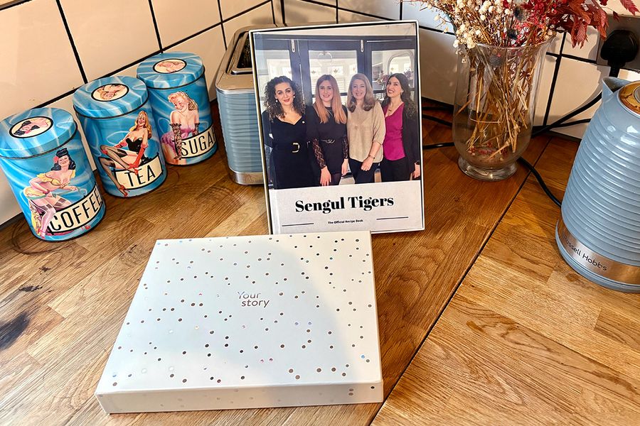 Le livre de recettes familial personnalisé de Sarah est présenté dans un coffret cadeau Photobox, illustrant comment un livre de recettes personnalisé fait un cadeau plein d'attention pour les anniversaires et autres occasions spéciales.