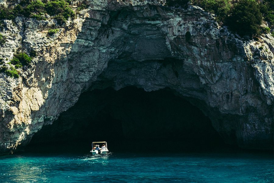 Un bateau entre dans des grottes marines à Corfou, illustrant la douceur de vivre et la beauté d'des vacances en septembre sur une île grecque.