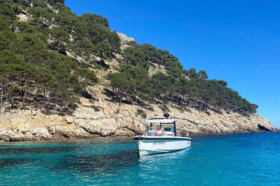 Un couple est assis sur un bateau près d'une magnifique côte accidentée à Ibiza, illustrant le côté plus tranquille des vacances en septembre sur l'île.