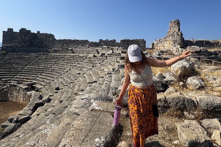 Gemma, rédactrice chez Photobox, marche parmi les rochers d'un amphithéâtre à Kalkan, en Turquie, illustrant comment choisir la bonne destination de septembre pour ses vacances.