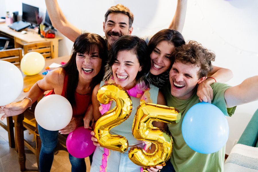 Un groupe de jeunes se rassemble autour de ballons formant le chiffre « 25 », souriant et posant pour une photo, illustrant les conseils de Photobox pour capturer les moments marquants d'un anniversaire.