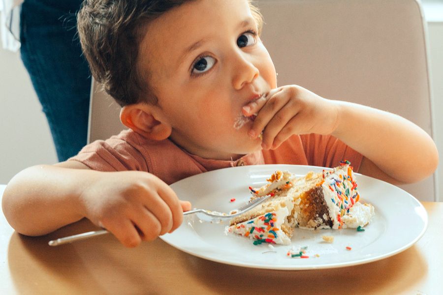 Un petit garçon mange du gâteau d'anniversaire, illustrant la check-list photo de Photobox pour capturer les meilleurs moments d'une fête d'anniversaire pour enfants.