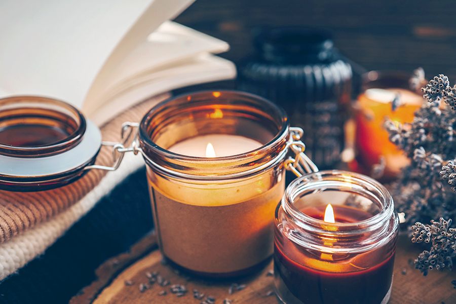 Quelques bougies allumées sont posées à côté d'un brin de fleurs, illustrant comment les bougies créent une atmosphère d'automne chaleureuse dans les conseils de déco hygge de Photobox.