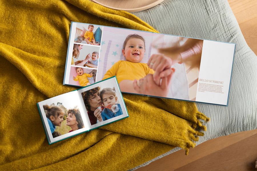 Deux livres photo personnalisés sont ouverts sur des photos de famille, posés sur un plaid jaune moutarde, illustrant comment les livres photo Photobox trouvent leur place dans une maison hygge.