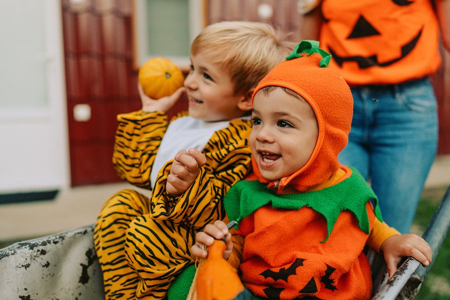 Deux enfants déguisés pour Halloween, l'un en citrouille et l'autre en tigre, illustrant les citations et phrases mignonnes d'Halloween pour Instagram de Photobox.